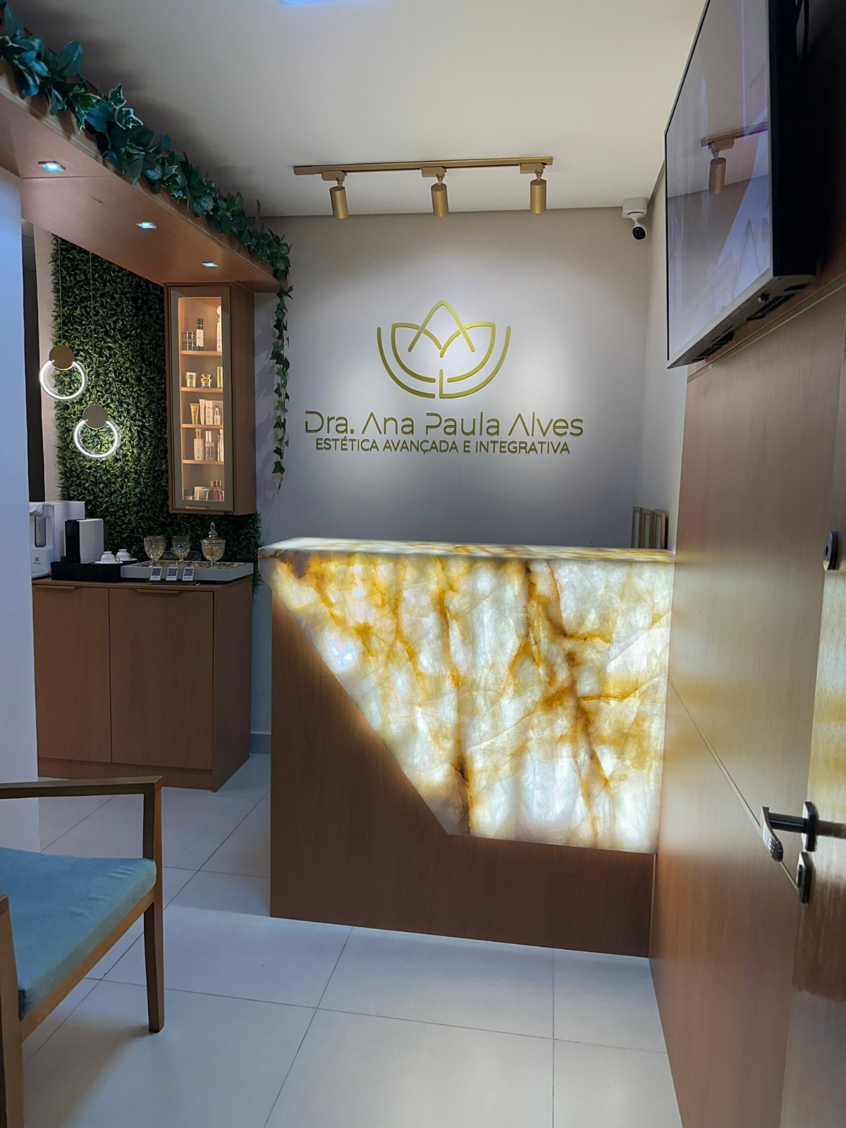 Recepção da clínica com balcão iluminado e logo da Dra. Ana Paula Alves